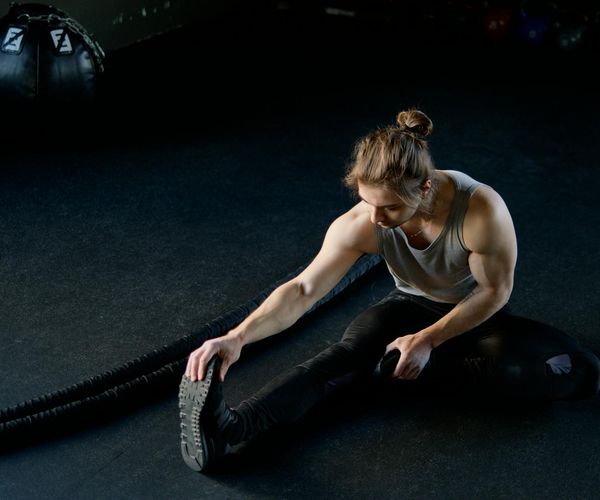 Athletic man performing stretching exercises in a modern gym.